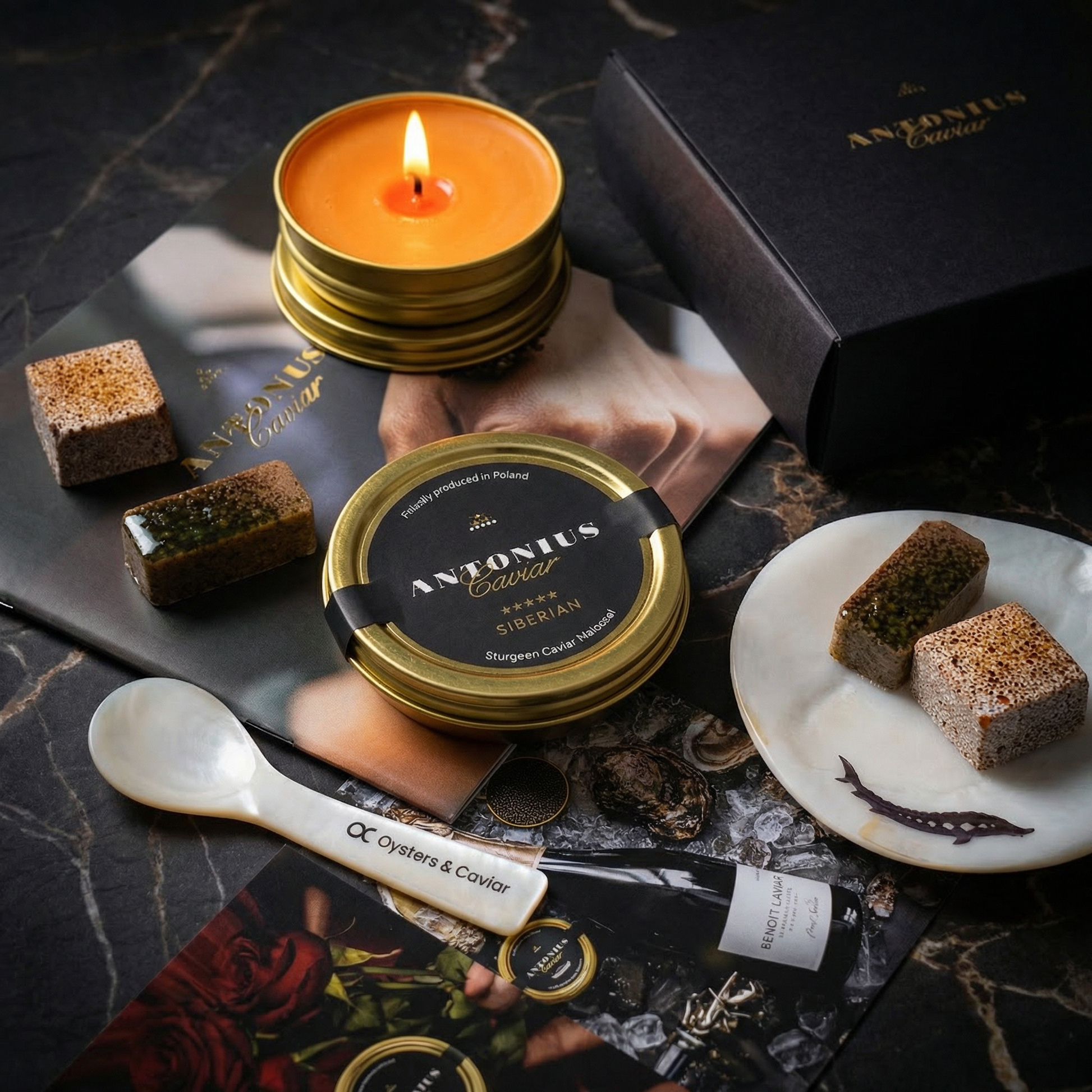 Antonius caviar, candle, mother-of-pearl spoon and plate, and chocolate truffles on a dark surface