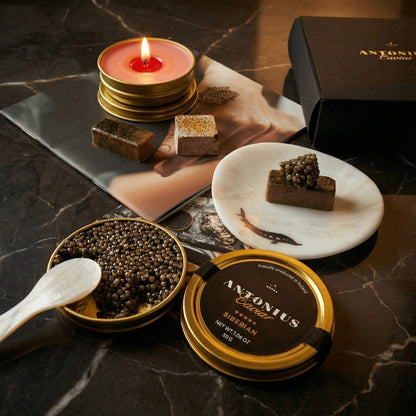 Caviar with a lit candle and pieces of chocolate on a marble surface, featuring Antonius Caviar branding.
